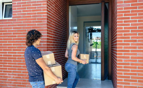 Couple taking cardboard boxes into home