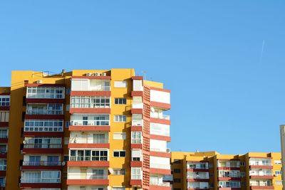 Low angle view of residential buildings against clear blue sky