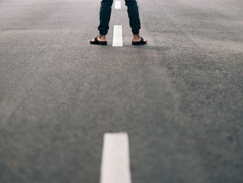 A boy standing in the middle of an empty road