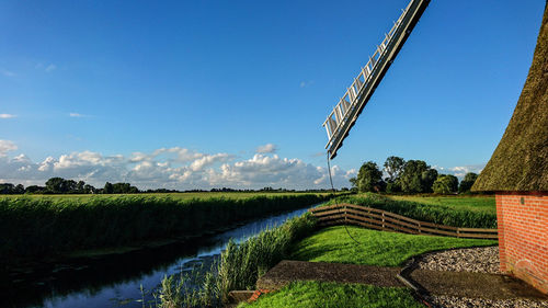 Cropped image of traditional windmill by canal against sky