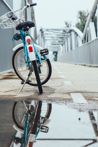 Bicycle parked by puddle on bridge