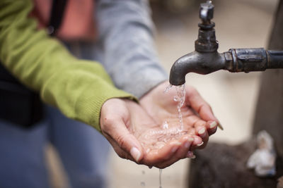 Close-up of hand holding faucet over water