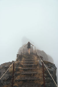 Low angle view of woman on steps against sky during foggy weather