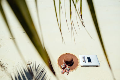 High angle view of sunhat with smart phone and sunglasses on beach