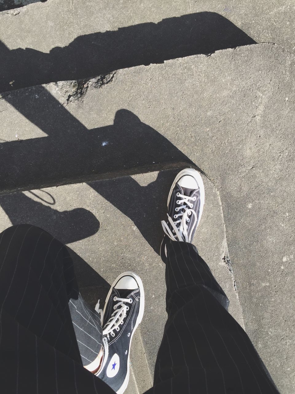 high angle view, low section, lifestyles, shadow, street, shoe, person, leisure activity, men, standing, personal perspective, road, sunlight, road marking, unrecognizable person, day, footwear