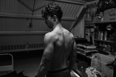 Shirtless man standing in workshop