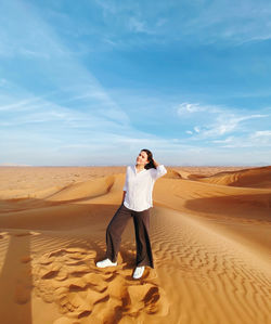 Rear view of woman standing at desert against sky