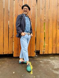 Full length portrait of smiling man standing against wall