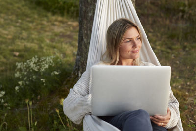 Woman using laptop on hammock