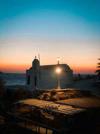 Illuminated building against sky during sunset