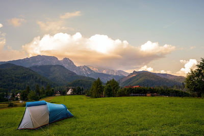 Tent on field by mountains against sky