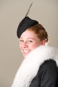 Portrait of smiling young woman with fur against beige background