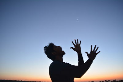 Silhouette man standing against clear sky during sunset