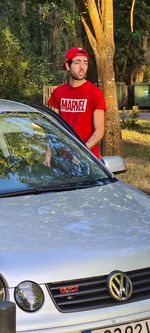 Portrait of young man standing by car