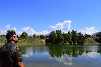 Reflection of man in lake against sky