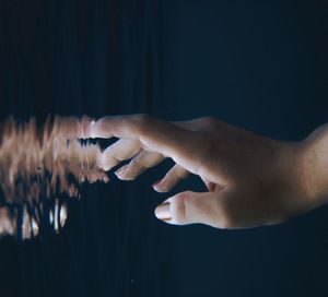 Hand reaching for its reflection underwater