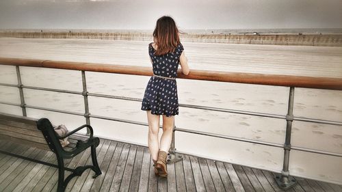 Rear view of woman standing by sea