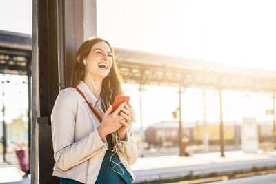 Laughing young woman talking on phone outdoors