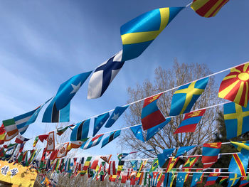 Low angle view of flags hanging against blue sky. flag installation