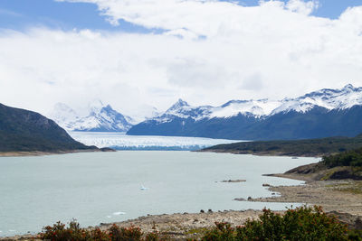 Scenic view of sea and snowcapped mountains against cloudy sky