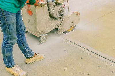 Low section of man working with machinery on footpath