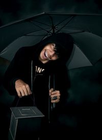 Portrait of smiling woman holding umbrella standing in rain