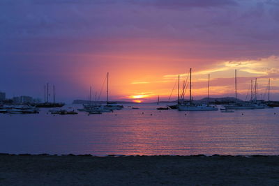 Sailboats in sea at sunset