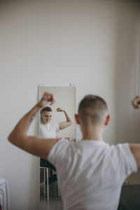 Portrait of man holding camera while standing against wall