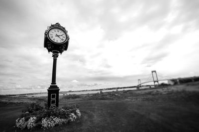 Clock on field against sky