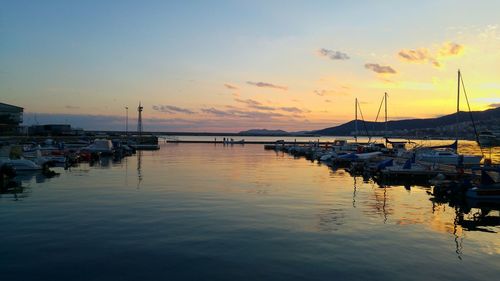 Sailboats moored at harbor against sky during sunset