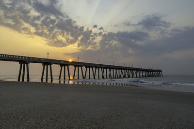 Pier over sea against sky during sunset