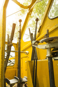 The old yellow digger was parked in a park. ,inside the loader gear