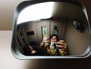 Reflection of woman taking selfie in mirror of elevator