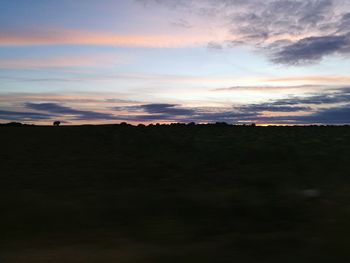 Scenic view of silhouette field against sky at sunset