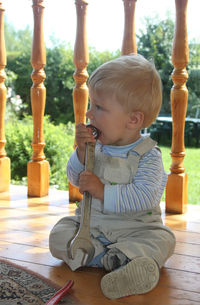 Cute boy sitting eating wrench while sitting on floor