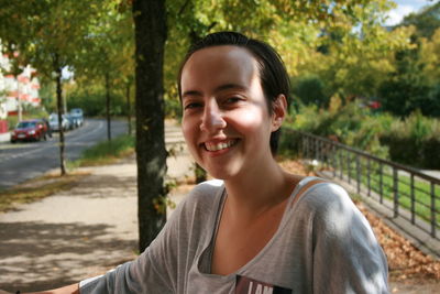 Portrait of smiling young woman against trees