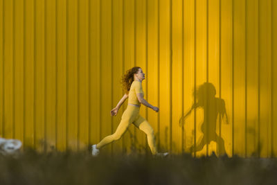 Woman running in front of yellow wall
