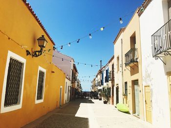 Alley amidst buildings against clear sky