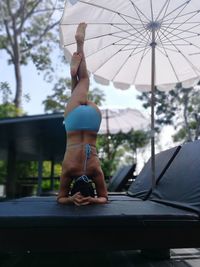 Full length of young woman in bikini exercising on lounge chair