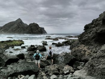 Rear view of rocks on beach against sky