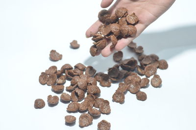Close-up of hand holding ice cream over white background