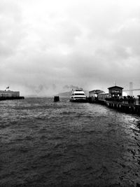 Boats in sea against cloudy sky