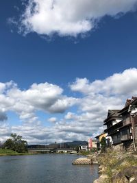 Buildings by river against sky