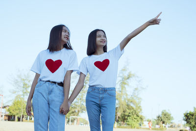 Woman with heart shape against sky