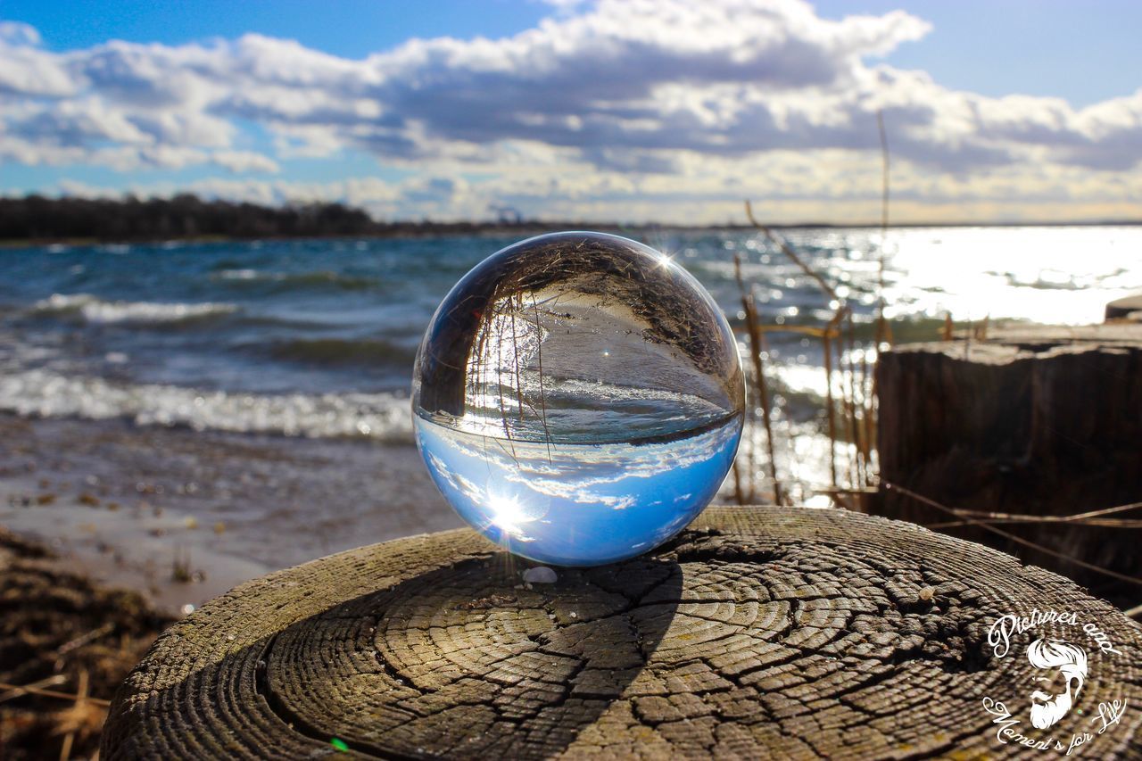 CLOSE-UP OF DRINKING GLASS ON BEACH