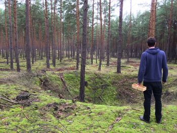 Man standing on tree trunk in forest