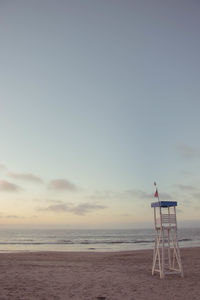 Lifeguard hut on beach against sky during sunset