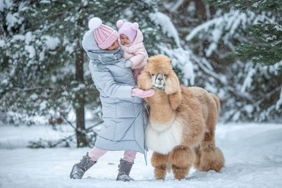 Portrait of woman with dog on snow covered field