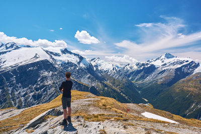 Rear view of woman standing on snowcapped mountain against sky