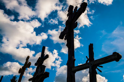 Low angle view of cross sculpture against blue sky